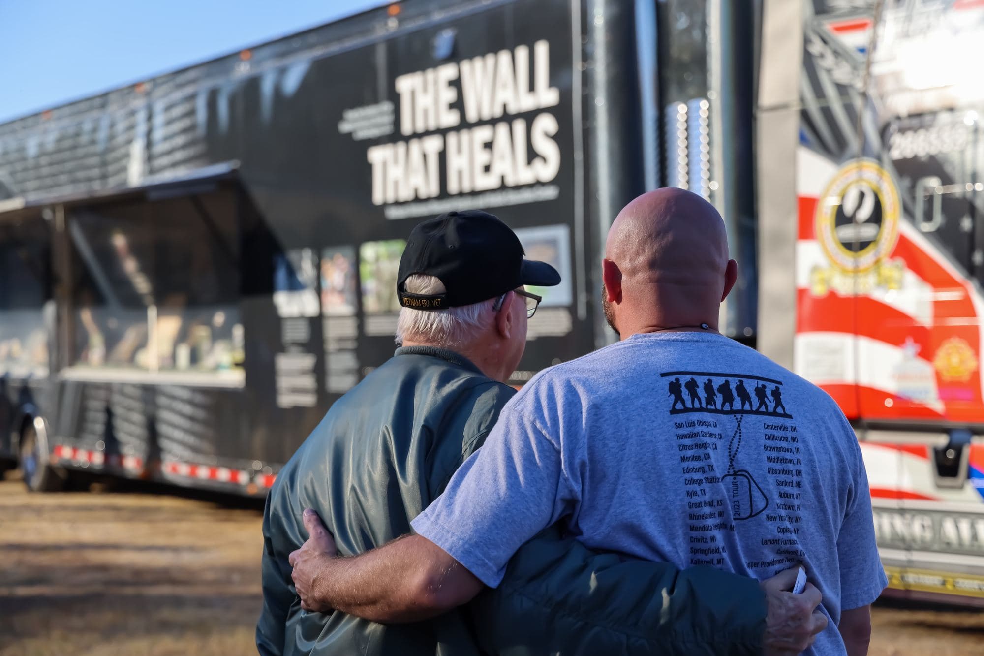 Two veterans embrace in front of The Wall That Heals trailer after the escort arrives